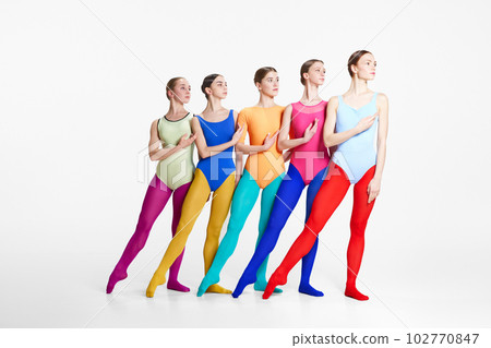 Group of young girls, professional ballet dancer in colorful bodysuits and tights standing in position against grey studio background Group of young girls, professional ballet dancer in colorful bodysuits and tights standing in position against grey studio background 102770847