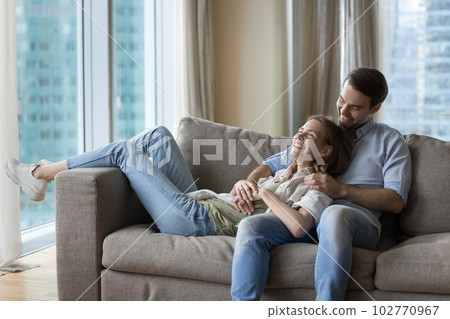 Happy husband and wife resting on cozy sofa together Happy husband and wife resting on cozy sofa together 102770967