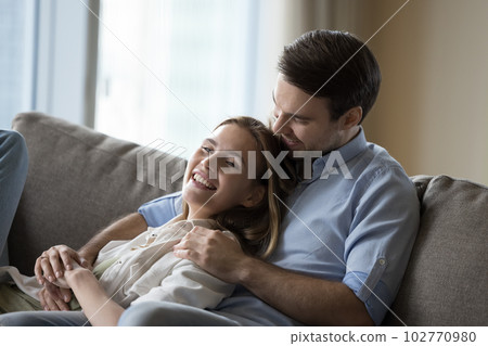 Cheerful dating couple in love resting on comfortable couch Cheerful dating couple in love resting on comfortable couch 102770980