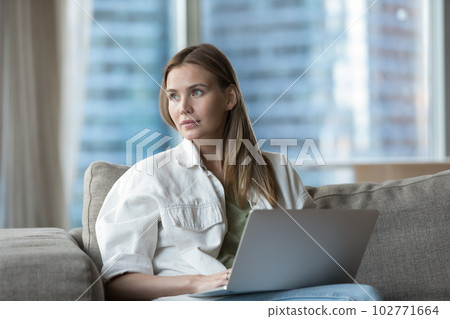 Dreamy beautiful young freelancer woman working at laptop 102771664