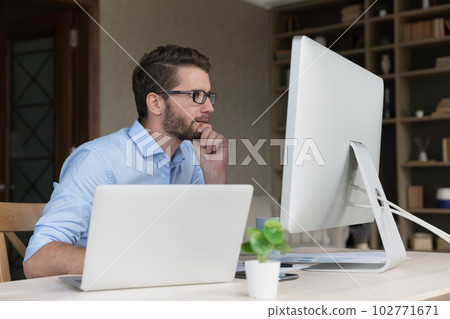 Serious busy young freelancer man working on online project Serious busy young freelancer man working on online project 102771671