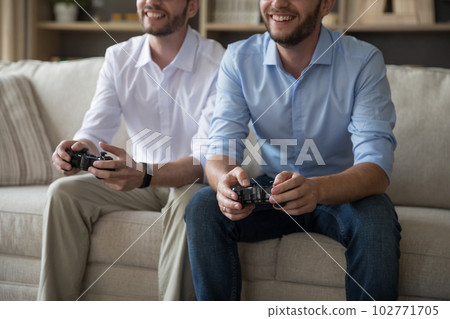 Cheerful positive adult similar twins playing video game Cheerful positive adult similar twins playing video game 102771705