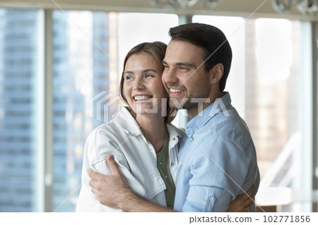 Happy dreamy young husband and wife hugging at new home 102771856