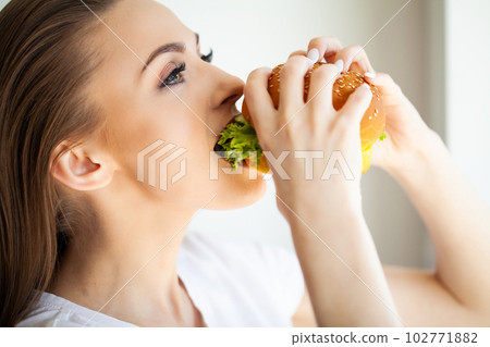 Young woman eating hamburger woman eating junk food Young woman eating hamburger woman eating junk food 102771882