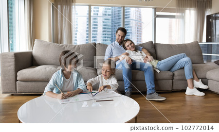 Happy couple of parents relaxing on big soft cozy couch Happy couple of parents relaxing on big soft cozy couch 102772014