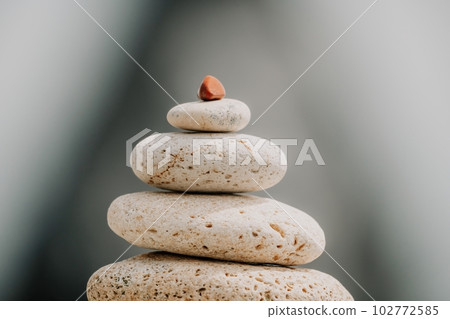 balanced rock pyramid stands tall on sea pebble beach. Selective focus highlights zen stones on the beach, evoking feelings of calm, harmony, and balance. Perfect for meditation or spa concepts. 102772585