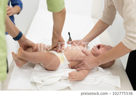 Baby beeing vaccinated by pediatrician in presence of his mother. Preventive vaccination against Diphtheria, whooping cough, tetanus, hepatitis, haemophilus influenzae, pneumococcus, poliomyelitis. 102775536