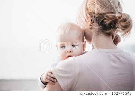 Tender woman caressing her little baby boy infant child outdoors. Mother's unconditional love for her child. Tender woman caressing her little baby boy infant child outdoors. Mother's unconditional love for her child. 102775545