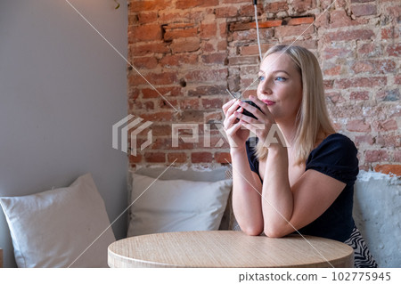 Pondering attractive blonde young woman with coffee in hand thinking on plans enjoying recreation 102775945