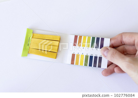 Test strips to measure Ph on a white background in a woman's hand 102776084