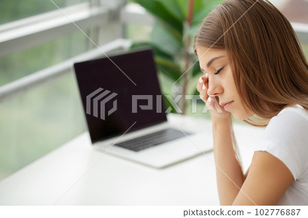 Portrait of tired young business woman with laptop computer 102776887