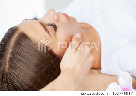 Beautiful girl has a facial massage in a beauty clinic. Beautiful girl has a facial massage in a beauty clinic. 102776917