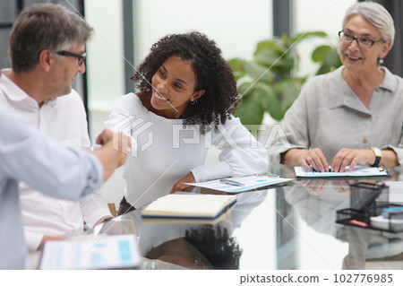 Negotiations in the office. Cheerful businesswoman shaking hands with colleague 102776985