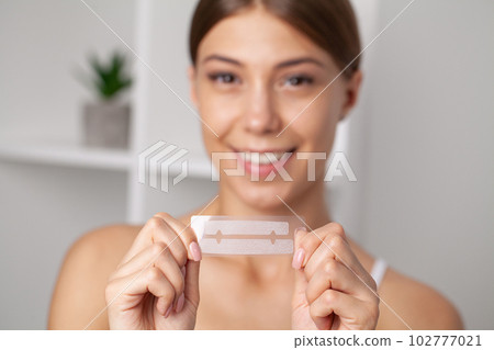 Teeth Whitening, Beautiful Smiling Woman Holding Whitening Strip. Teeth Whitening, Beautiful Smiling Woman Holding Whitening Strip. 102777021