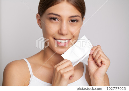 Teeth Whitening, Beautiful Smiling Woman Holding Whitening Strip. Teeth Whitening, Beautiful Smiling Woman Holding Whitening Strip. 102777023