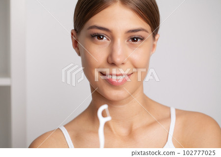 Woman using dental floss for cleaning her teeth Woman using dental floss for cleaning her teeth 102777025
