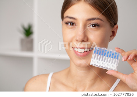 The woman uses brushes to clean the interdental spaces The woman uses brushes to clean the interdental spaces 102777026