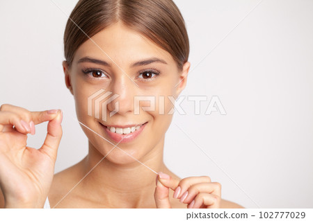 Woman using dental floss for cleaning her teeth Woman using dental floss for cleaning her teeth 102777029