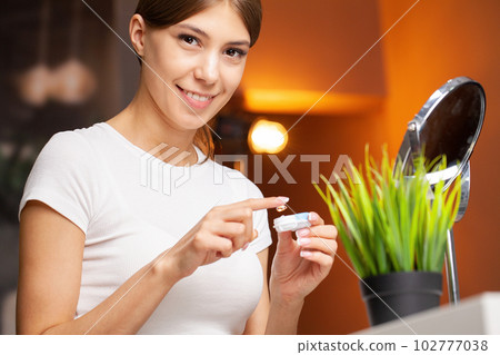 Young woman putting contact lens in her eye, close up Young woman putting contact lens in her eye, close up 102777038