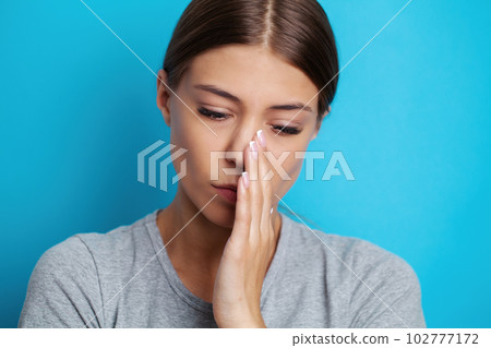 Woman suffering from tooth pain and touching cheek 102777172
