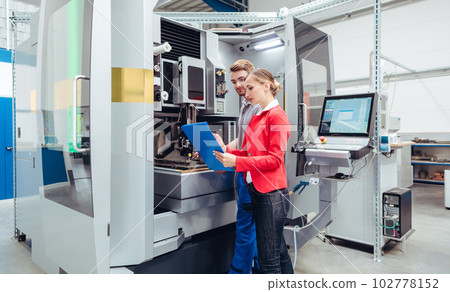 Worker and manager discussing production at a machine tool Worker and manager discussing production at a machine tool 102778152