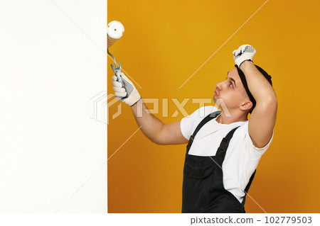 young man in working clothes painting white walls young man in working clothes painting white walls 102779503