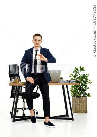 Successful caucasian businessman holding toy house in the office. real estate insurance 102779552