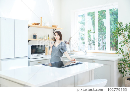 Young woman with a cup in the kitchen Young woman with a cup in the kitchen 102779563
