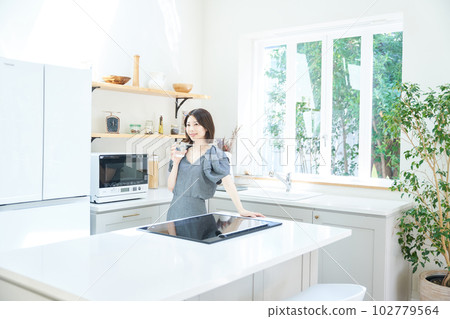 Young woman with a cup in the kitchen 102779564