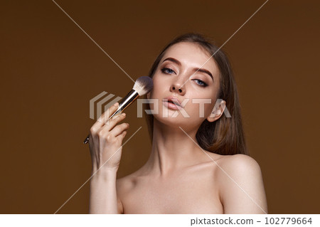 woman applying blush on cheeks with make-up brush woman applying blush on cheeks with make-up brush 102779664
