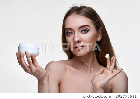beautiful smiling young woman applying skin care cream on her face beautiful smiling young woman applying skin care cream on her face 102779681