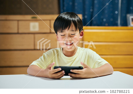 Elementary school boy playing a game on a smartphone Elementary school boy playing a game on a smartphone 102780221