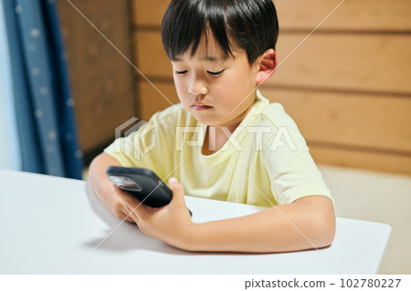 在智能手機上觀看視頻的小學生 在智能手機上觀看視頻的小學生 102780227
