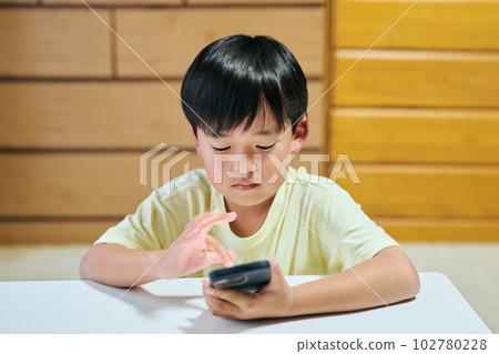 Elementary school boy watching videos on smartphone 102780228