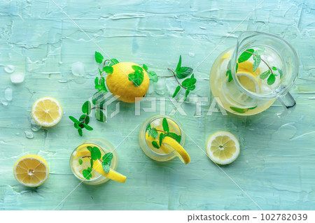 Lemonade with mint. Lemon water drink with ice. Two glasses and a pitcher 102782039