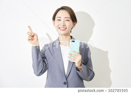 Business woman holding a smartphone and pointing to the left White background 102785505
