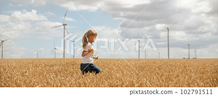 Profile side view little cute happy blond caucasian girl enjoy walking ripe wheat ear field against wind mill turbine farm warm sunny summer day. Child freedom future clean energy environment concept Profile side view little cute happy blond caucasian girl enjoy walking ripe wheat ear field against wind mill turbine farm warm sunny summer day. Child freedom future clean energy environment concept 102791511