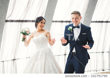 Happy beautiful newlyweds dancing near big windows Happy beautiful newlyweds dancing near big windows 102791790