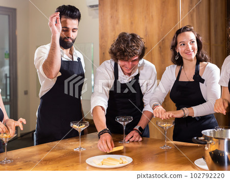 Chef teaching trainees how to make ice cream. Cooking tasty ice cream dessert made from chocolate and vanilla in glass bowl Chef teaching trainees how to make ice cream. Cooking tasty ice cream dessert made from chocolate and vanilla in glass bowl 102792220