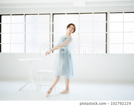 A woman practicing ballet in a bright room with windows A woman practicing ballet in a bright room with windows 102792229