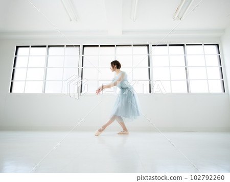 一個女人在有窗戶的明亮房間裡練習芭蕾舞 102792260
