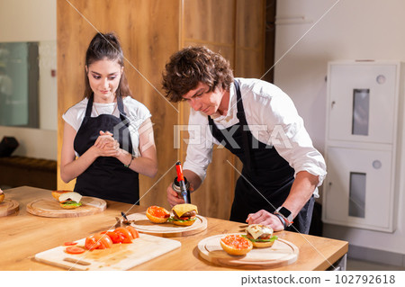 Preparing delicious burgers. Chef cooking meat burgers with beef, cheese and vegetables. Close-up Preparing delicious burgers. Chef cooking meat burgers with beef, cheese and vegetables. Close-up 102792618
