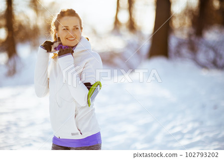 smiling fit woman in white jacket with headphones 102793202
