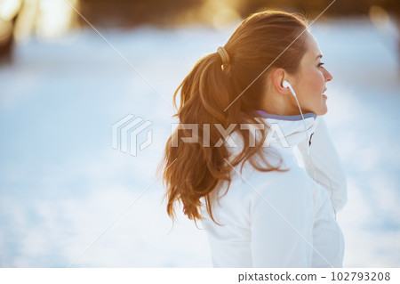 fit woman in white jacket with headphones fit woman in white jacket with headphones 102793208