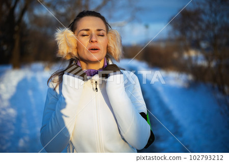 healthy woman in white jacket catching breath after exercise healthy woman in white jacket catching breath after exercise 102793212