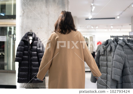 Rear view unrecognizable woman walking through clothing store 102793424