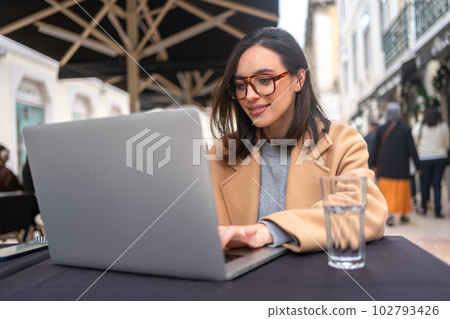 Woman working on remote from outdoor cafe 102793426
