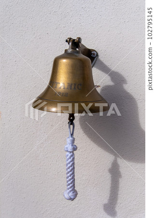 One small bell with the inscription Titanic and the date 1912. Brass bell on white wall 102795145
