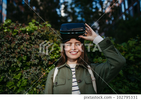 Portrait of young woman with virtual reality goggles outdoor. 102795331