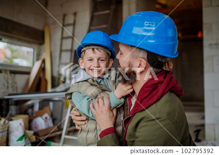 Father and his little son cuddling in their unfinished house. 102795392